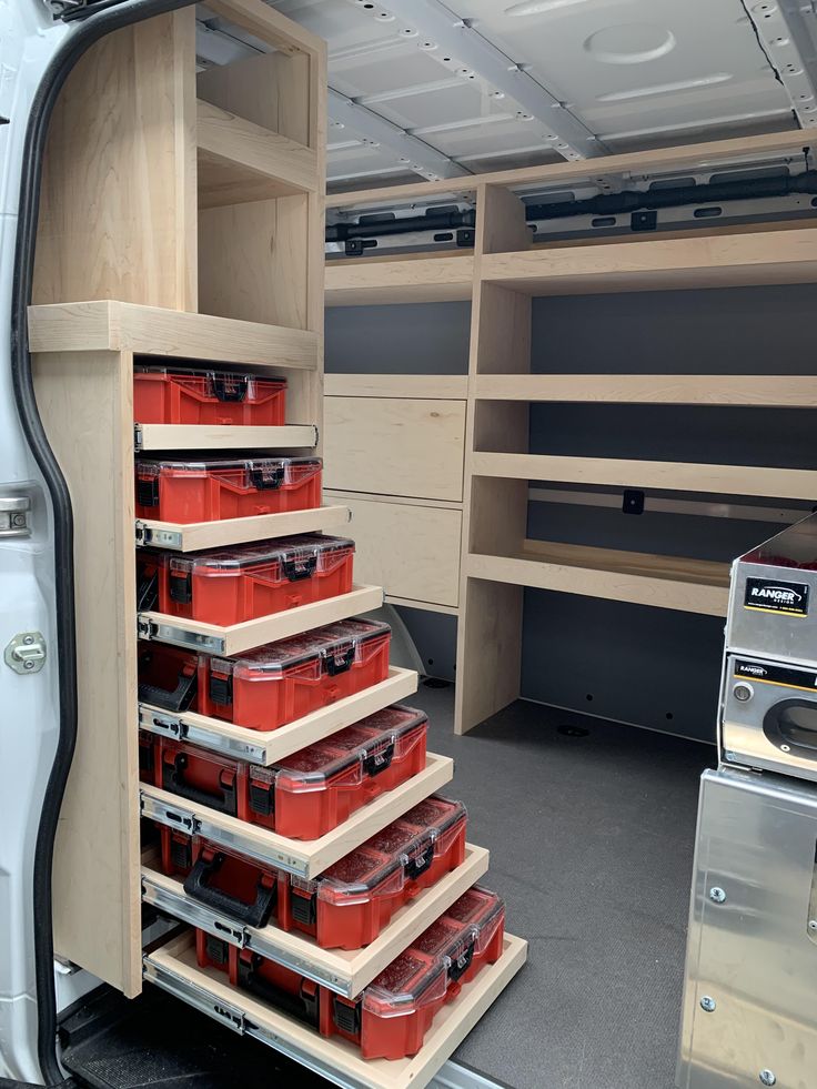 the inside of a van with many drawers and red bins in front of it