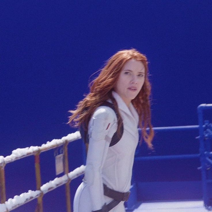 a woman dressed in white is standing by a railing