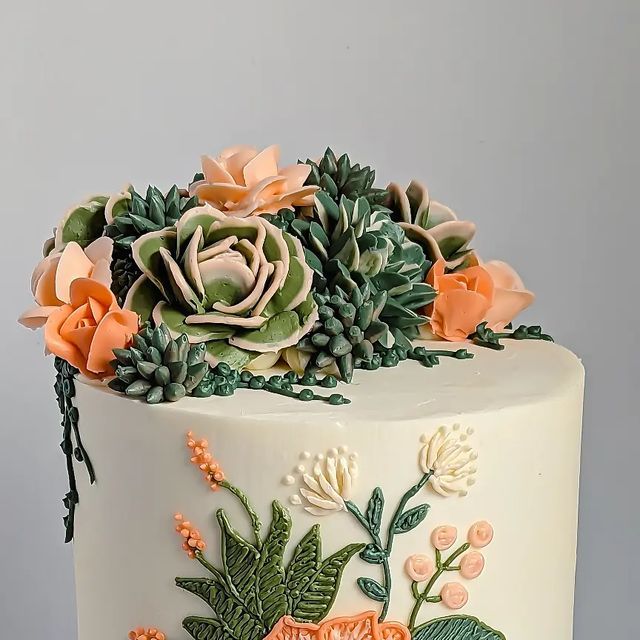 a white cake decorated with flowers and succulents