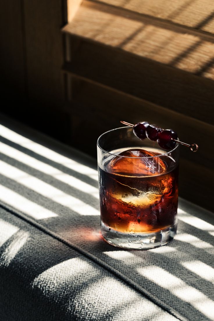 a glass filled with liquid sitting on top of a table next to a window sill