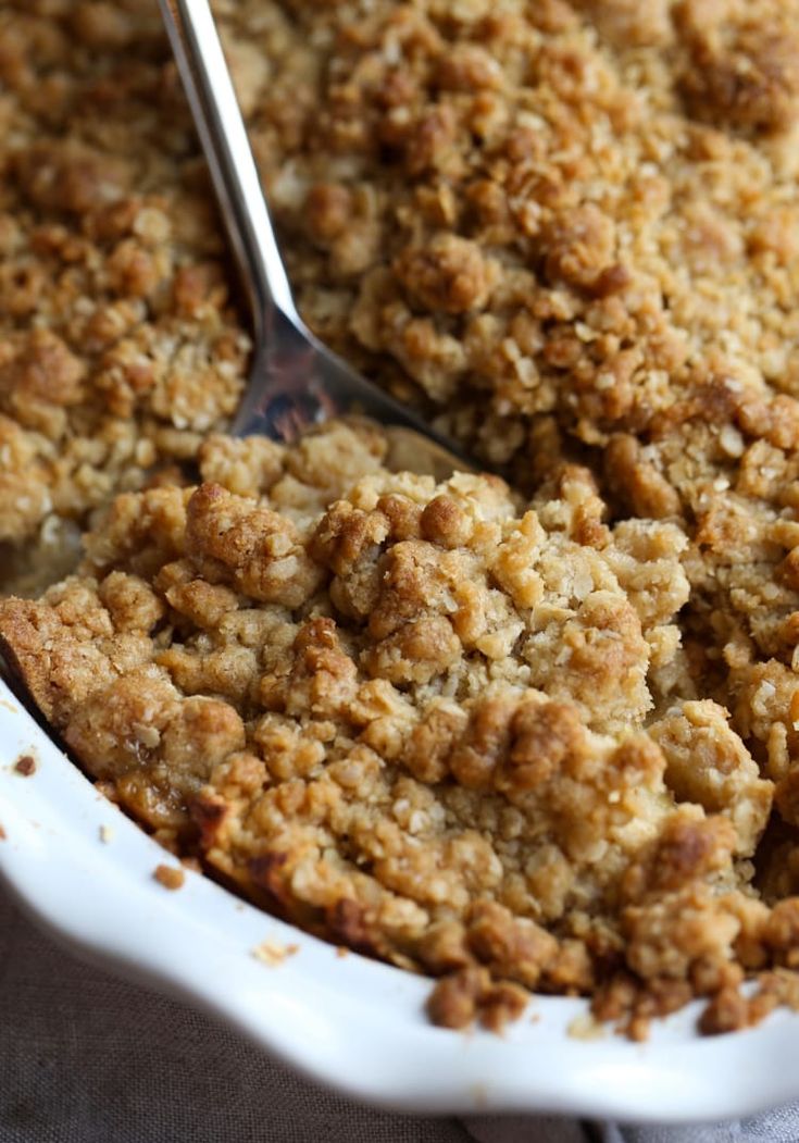 a close up of a spoon in a casserole dish with crumbs