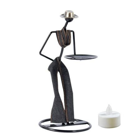 a candle holder with a statue on it next to a white candle and an empty container