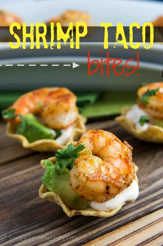 shrimp taco bites are served in shells on a wooden table with garnish