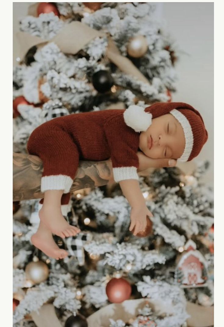 a baby laying on top of a christmas tree