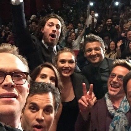 a group of people standing next to each other in front of a crowd with their hands up