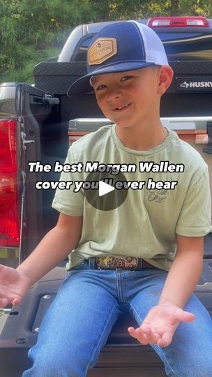 a young boy sitting in the back of a truck with his hand out to someone