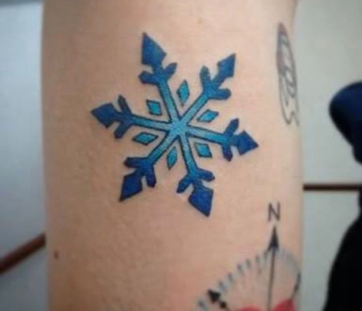 a snowflake tattoo on the leg of a woman