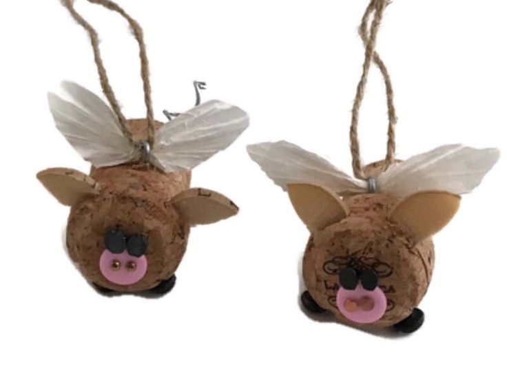 two brown pigs with white wings hanging from twine strings on each side of their heads