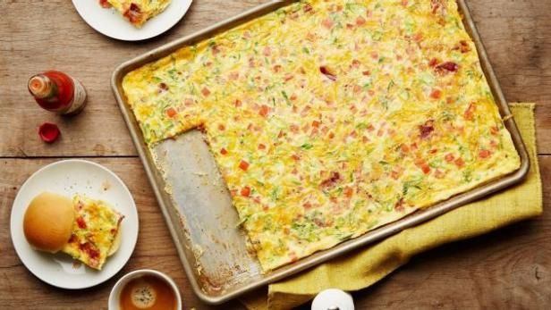 an omelet is sitting on a table next to plates and cups