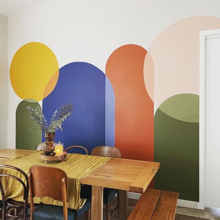 a dining room with colorful wallpaper and wooden table