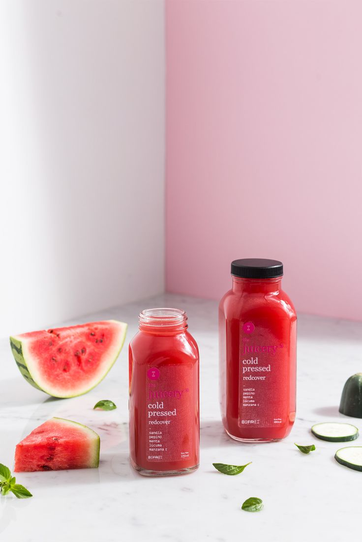 two jars filled with liquid next to slices of watermelon