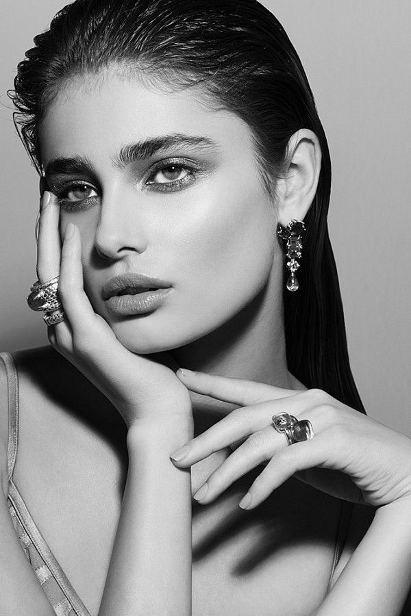 a woman with her hands on her face and wearing jewelry, posing for the camera