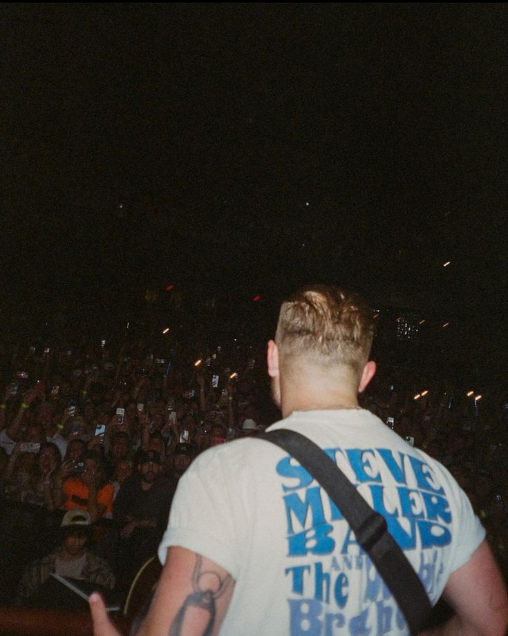 a man standing in front of an audience at a concert with his back to the camera