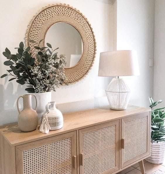 a white vase sitting on top of a wooden dresser next to a mirror and lamp