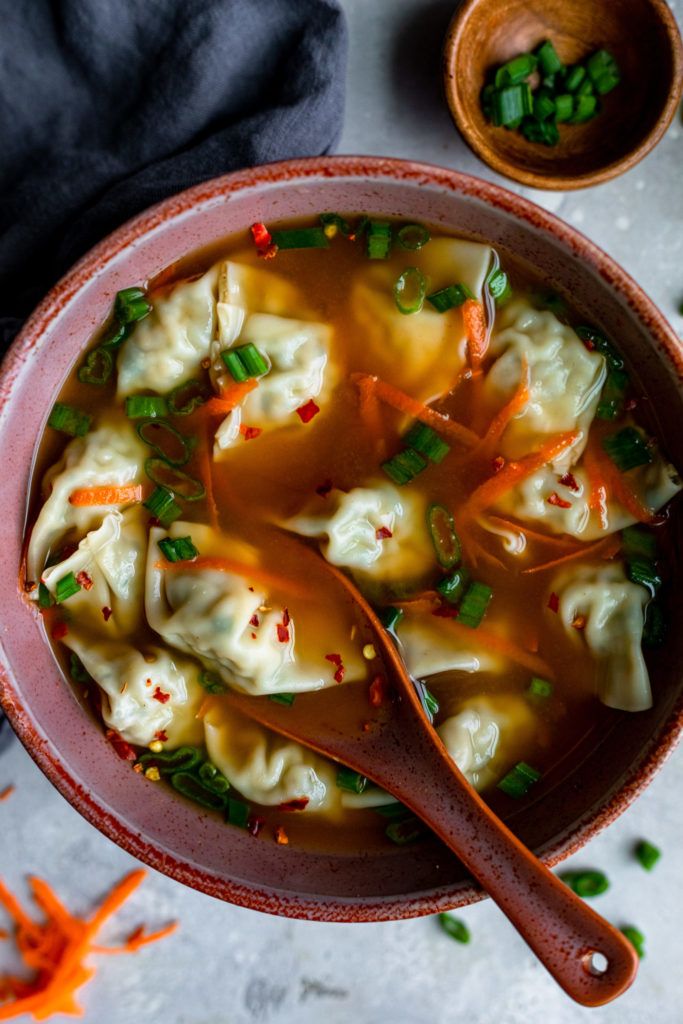 a bowl of dumplings with carrots and green onions