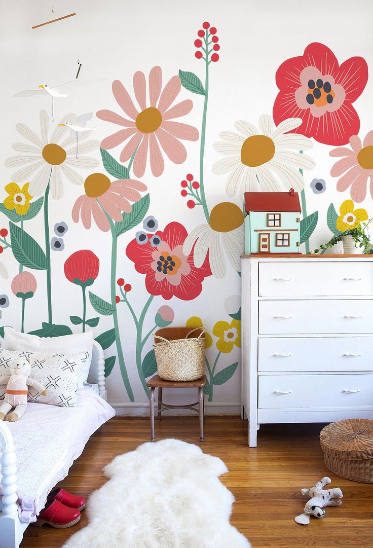 a child's bedroom with flowers painted on the wall and a white dresser next to it