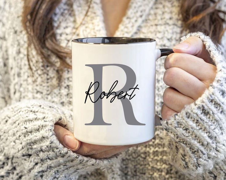 a woman is holding a coffee mug with the letter r on it in her hands