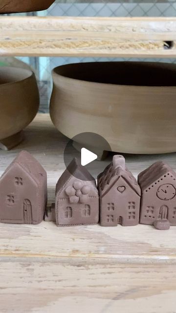 three clay houses sitting on top of a wooden table