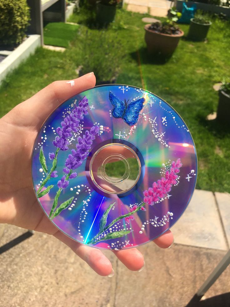 a person holding a cd in their hand with flowers and butterflies on the disc cover