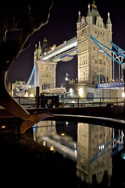 the tower bridge is lit up at night