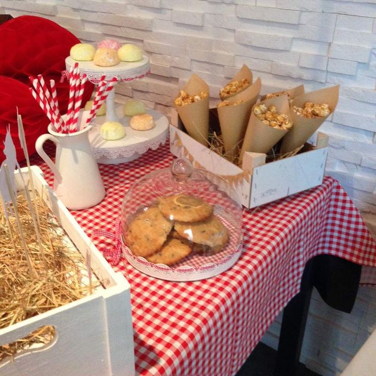 a red and white checkered table cloth with cookies on it, straw bales in the background