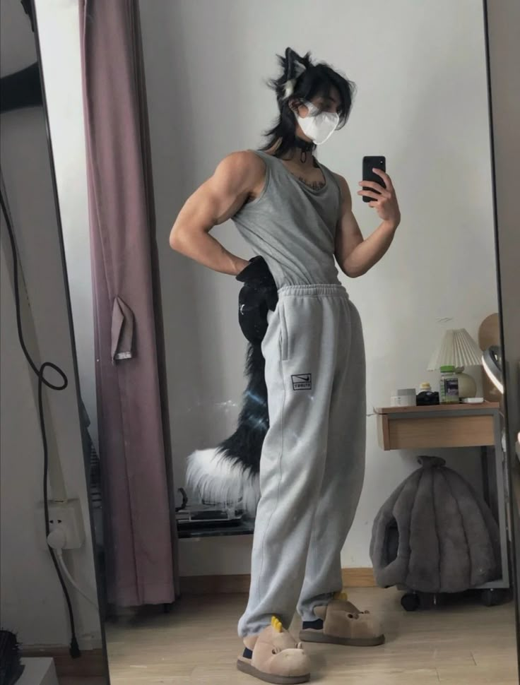 a woman in grey jumpsuits taking a selfie with her phone and cat