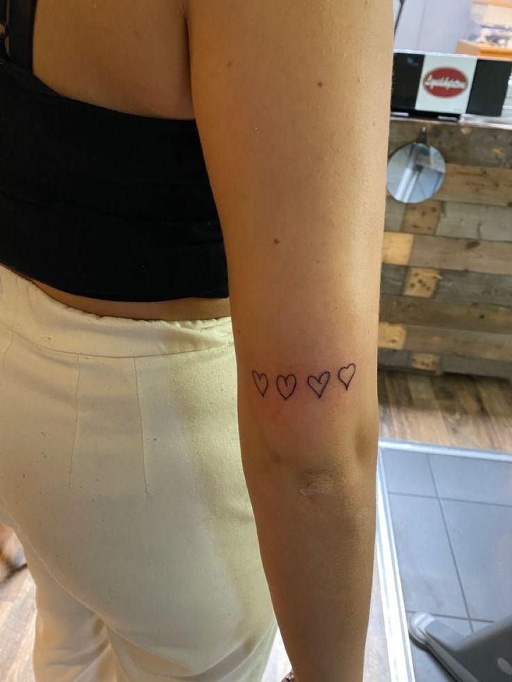 a woman's arm with three hearts tattooed on the left side of her right arm