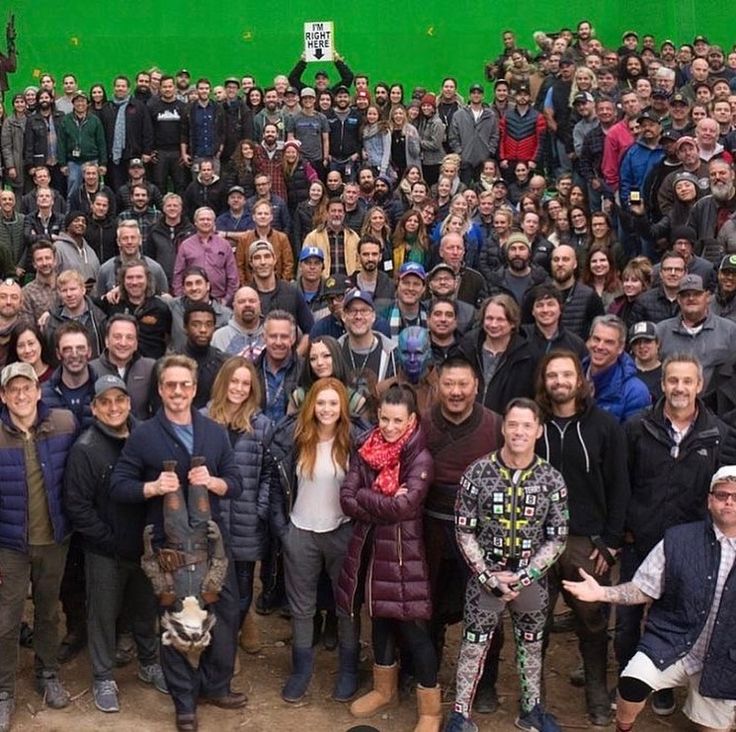 a large group of people standing in front of a green screen