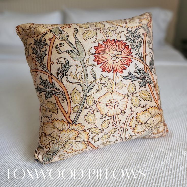 a decorative pillow on top of a bed with white sheets and pillows in the background