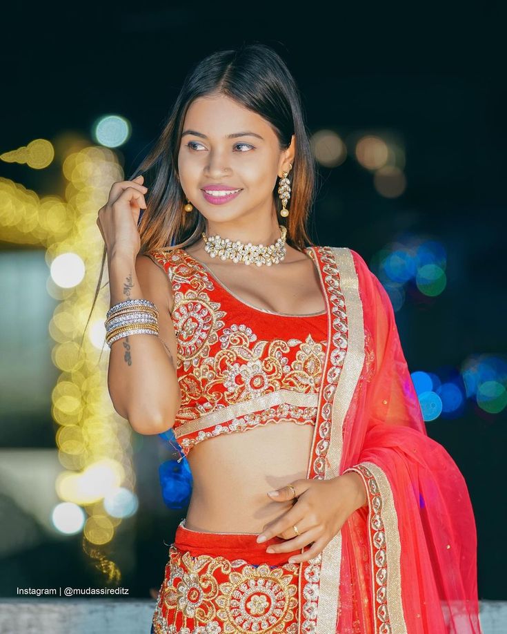 a beautiful young woman in a red and gold lehenga with her hand on her hip