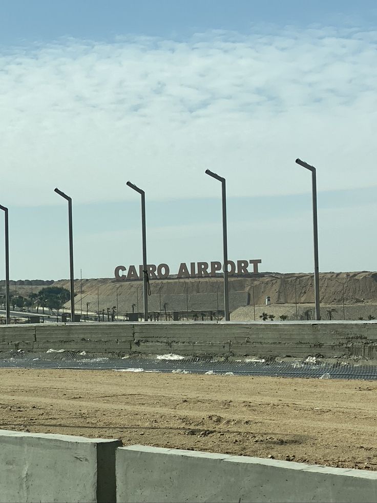 an airport sign is shown on the side of a road with several poles in front of it