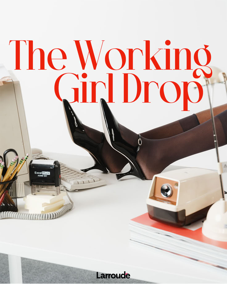 a woman's legs on top of a desk next to a computer and telephone