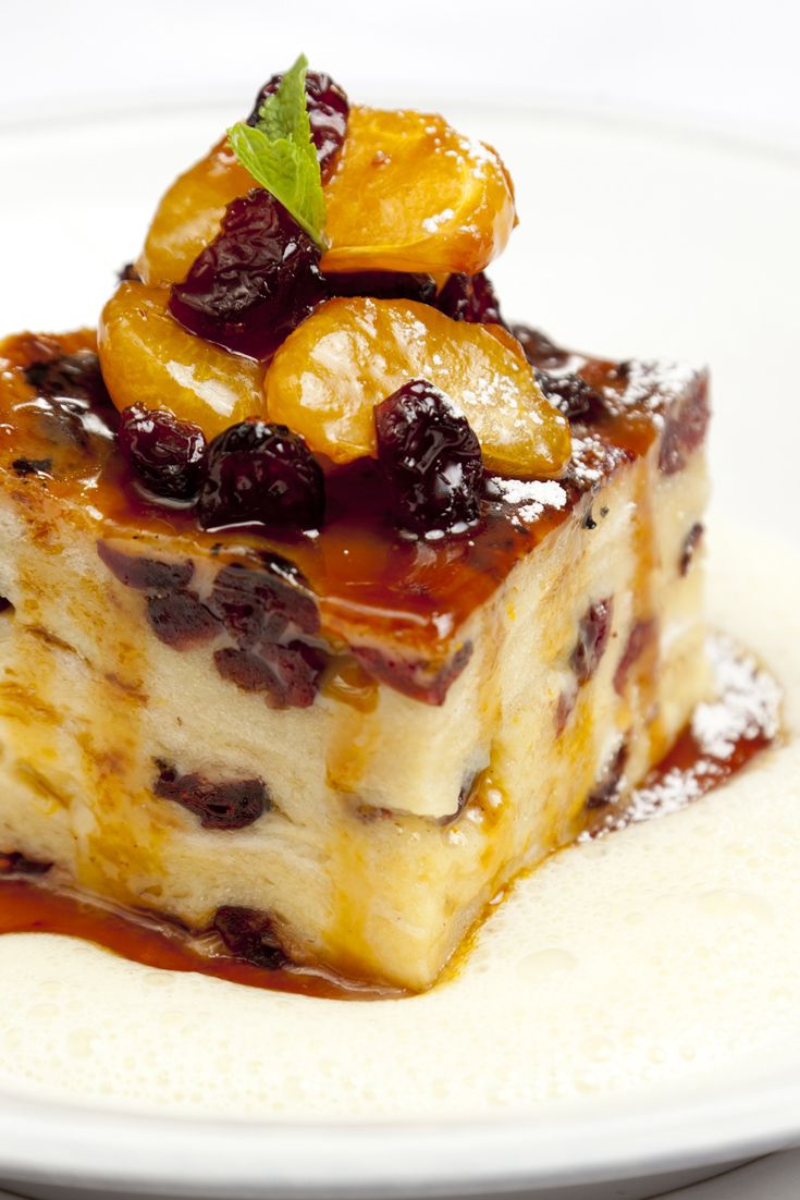 a piece of cake sitting on top of a white plate covered in syrup and fruit