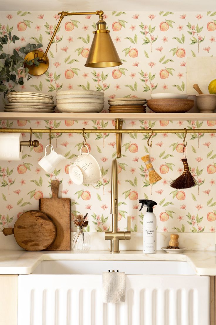 the kitchen is decorated with wallpaper and gold fixtures, including brass faucets