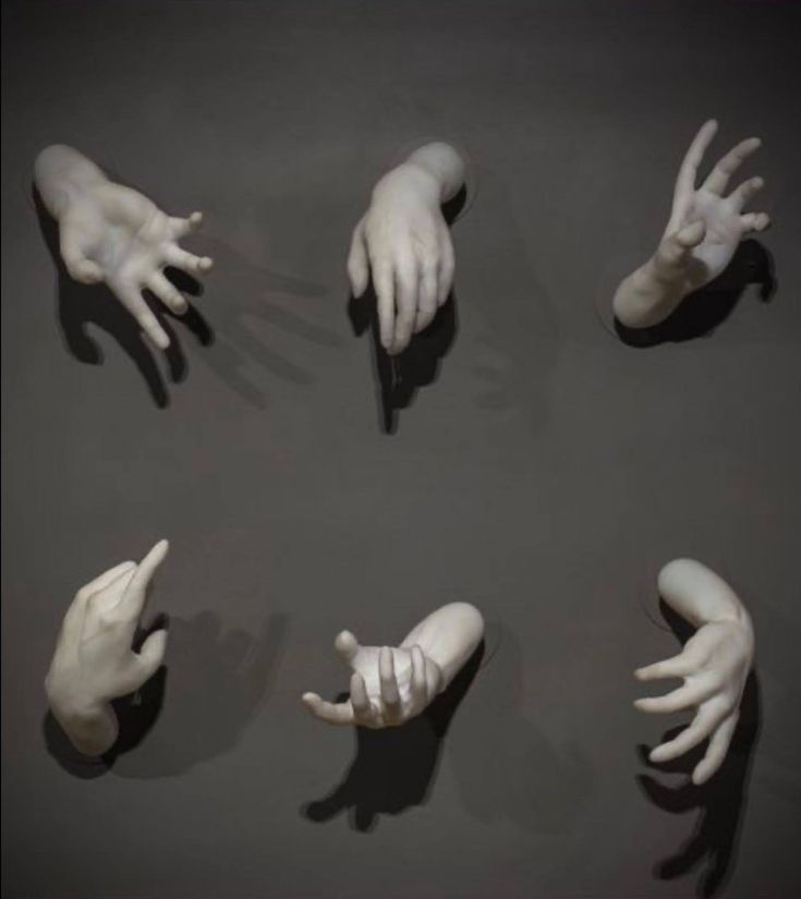 several hands are arranged in the middle of a circle on a gray surface with one hand reaching out