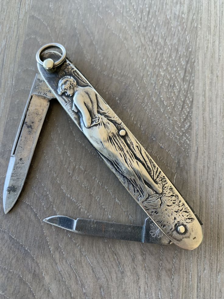 an old style pocket knife sitting on top of a wooden table next to a pair of scissors