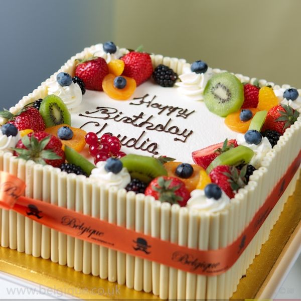 a birthday cake with fruit on it sitting on a table