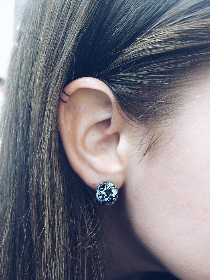 a close up of a person's ear with an earring in the shape of a skull