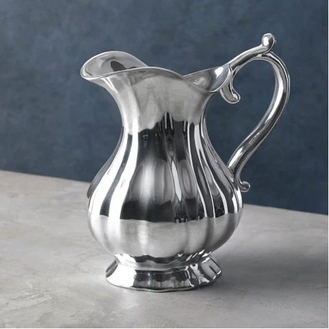 a silver pitcher sitting on top of a table