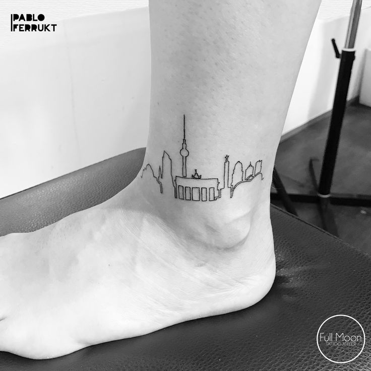 a black and white photo of a person's foot with a city skyline tattoo on it