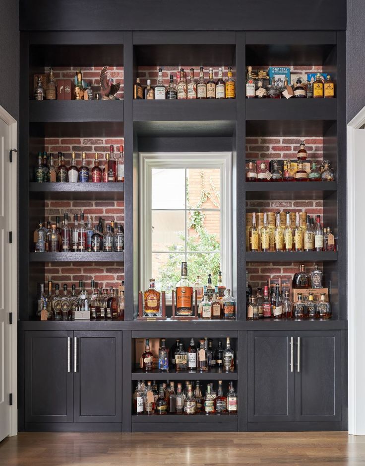 the shelves in this kitchen are full of bottles and spices, with one window open