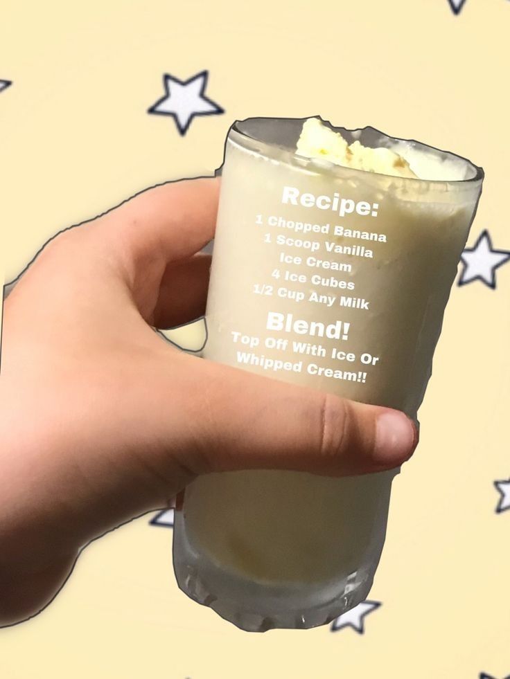 a hand holding up a cup filled with ice cream and whipped cream, on top of stars