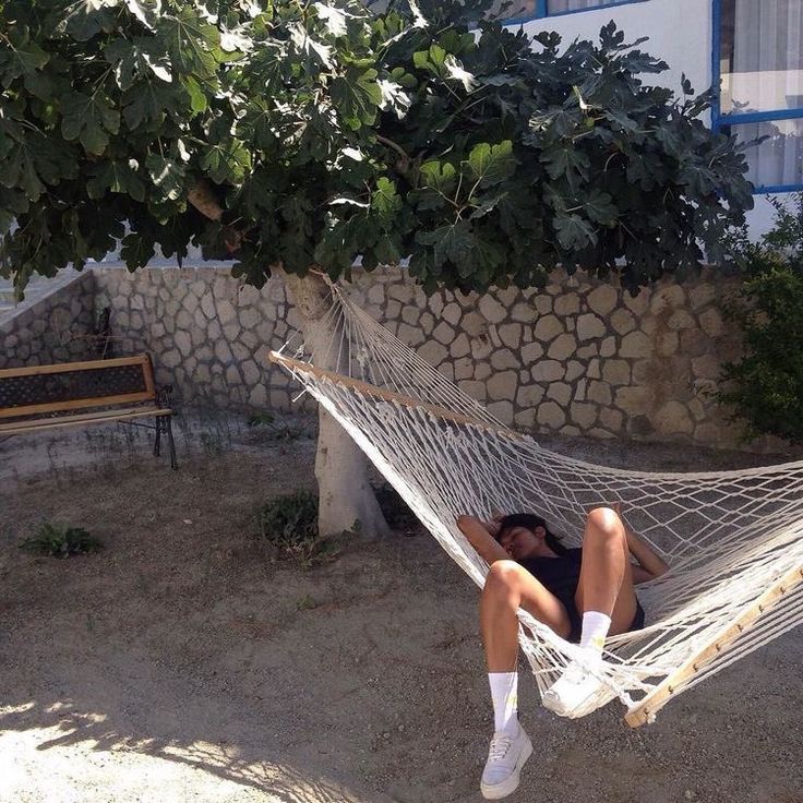 a woman is laying in a hammock outside