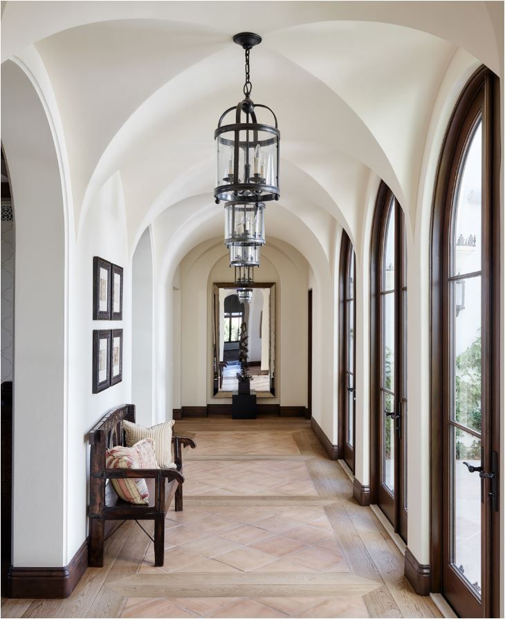 the hallway is lined with arched doorways and windows, along with a bench on one side