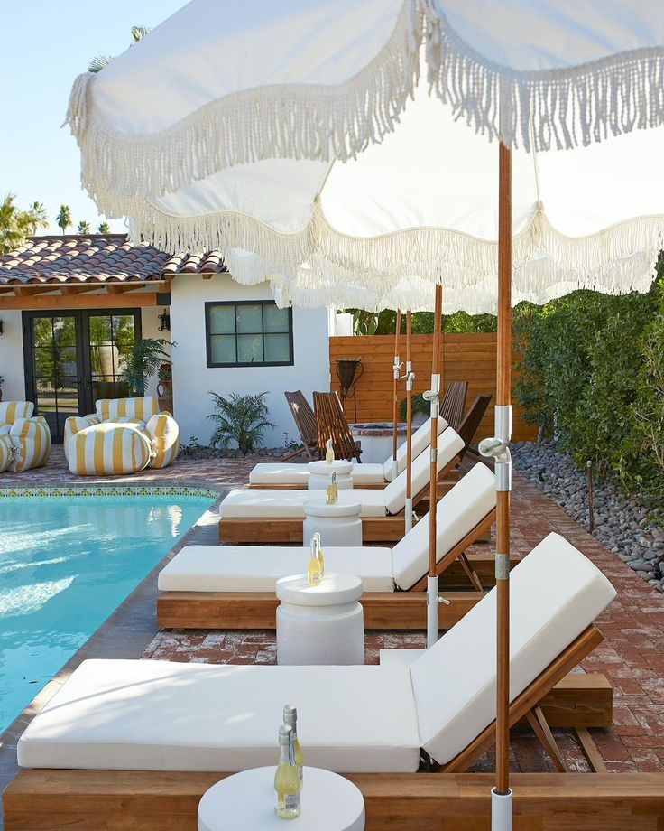 an outdoor pool with lounge chairs and umbrellas