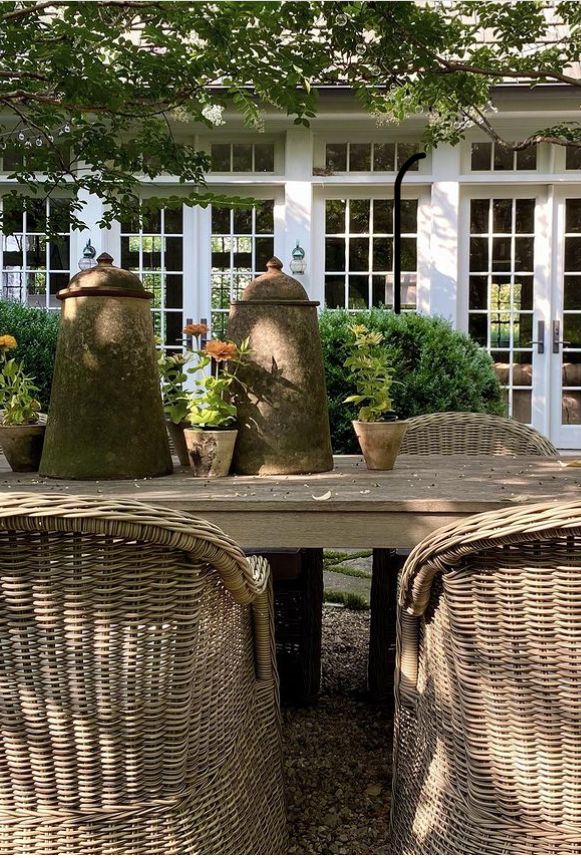 wicker chairs around a table with potted plants on it