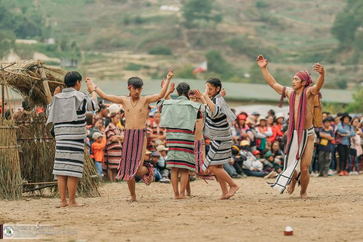 some people are dancing around in front of a large group of people on the beach