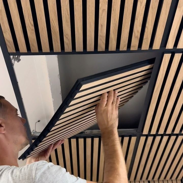 a man is working on the ceiling in his room with wood slats and black trim