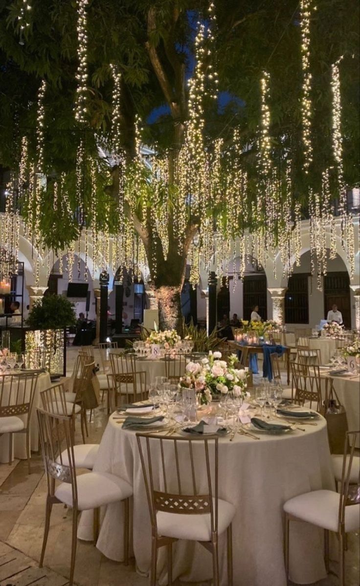 tables and chairs are set up for an event with lights hanging from the ceiling above them