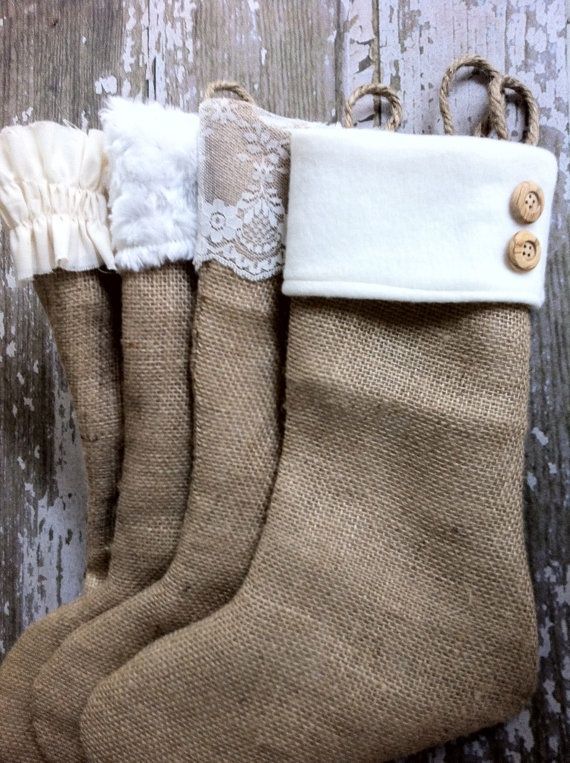 three burlap stockings with lace and buttons on them, hanging from a wooden wall